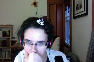 Photo is of the author staring, exhausted, into the computer camera. She has a tiny plastic tiara stuck, crooked, into her very messy hair. 